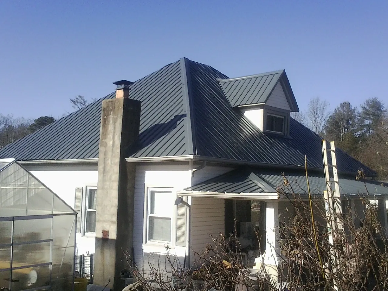 Dark blue standing seam metal roof on a white farmhouse with dormer — Slate & Tile Roof Repair by Roofing Brothers in American Canyon