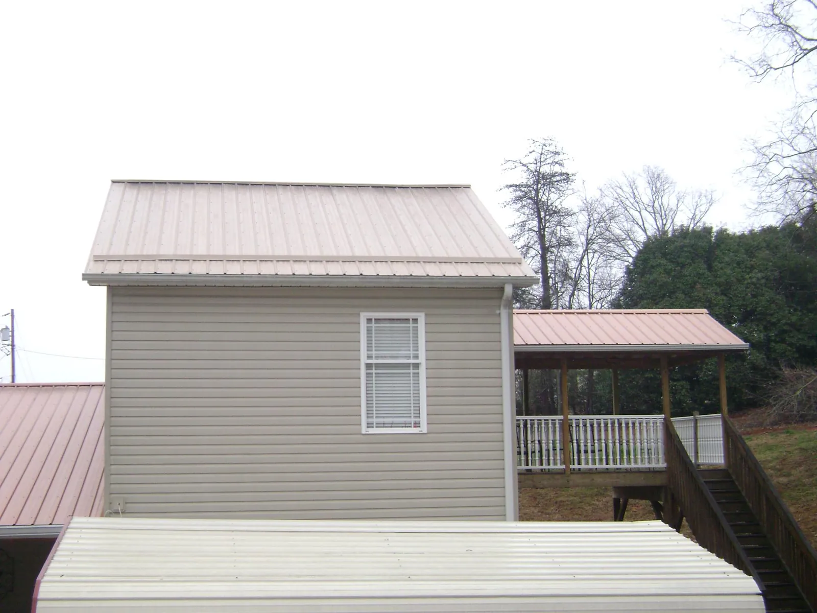 Tan metal roofs on a two story addition and attached porch, from a Roof Replacement job in American Canyon